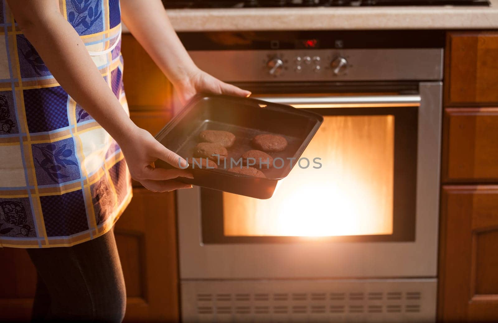 Closeup photo of woman putting cookies in oven