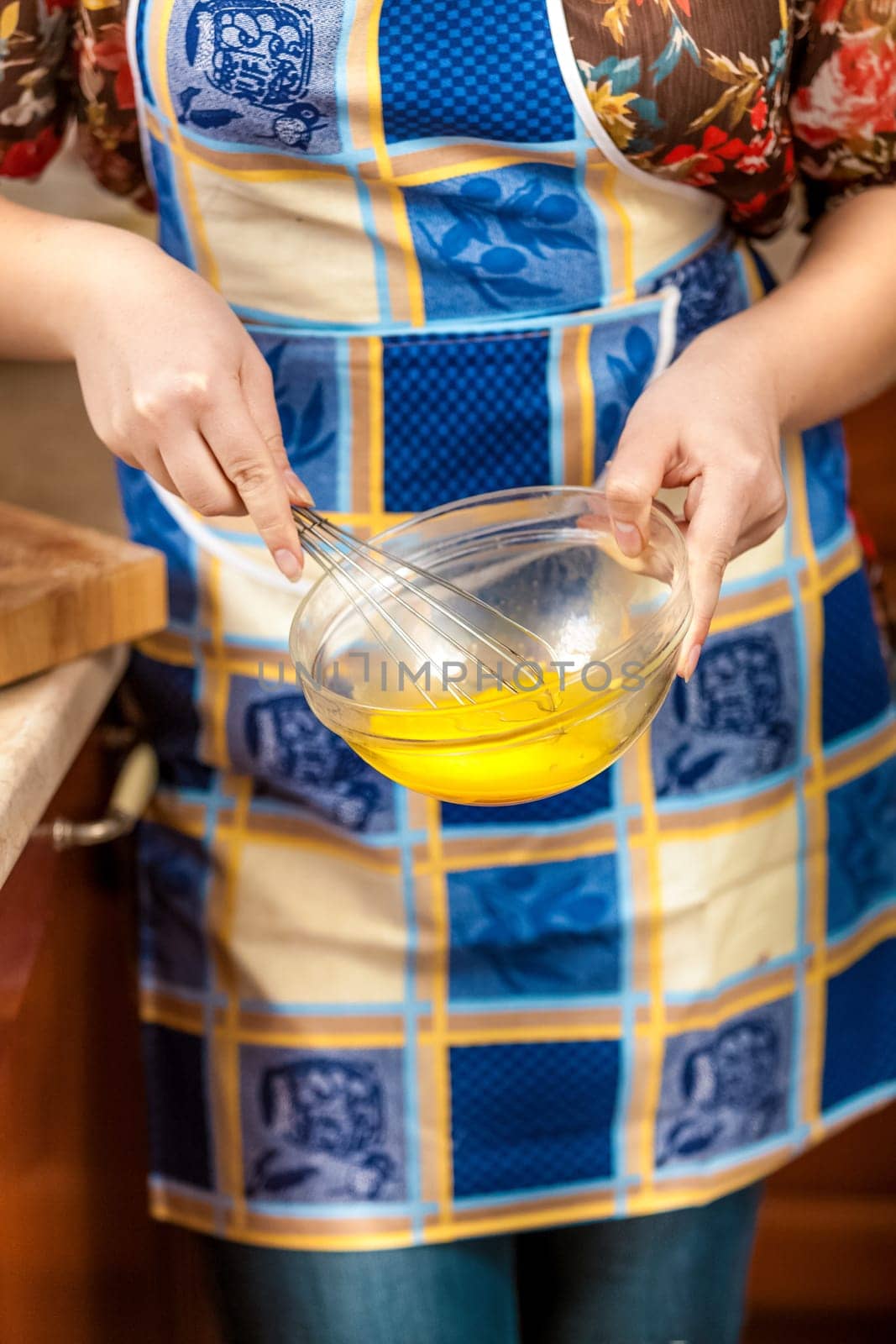 Closeup photo of housewife whisking egg yolk in glass bowl
