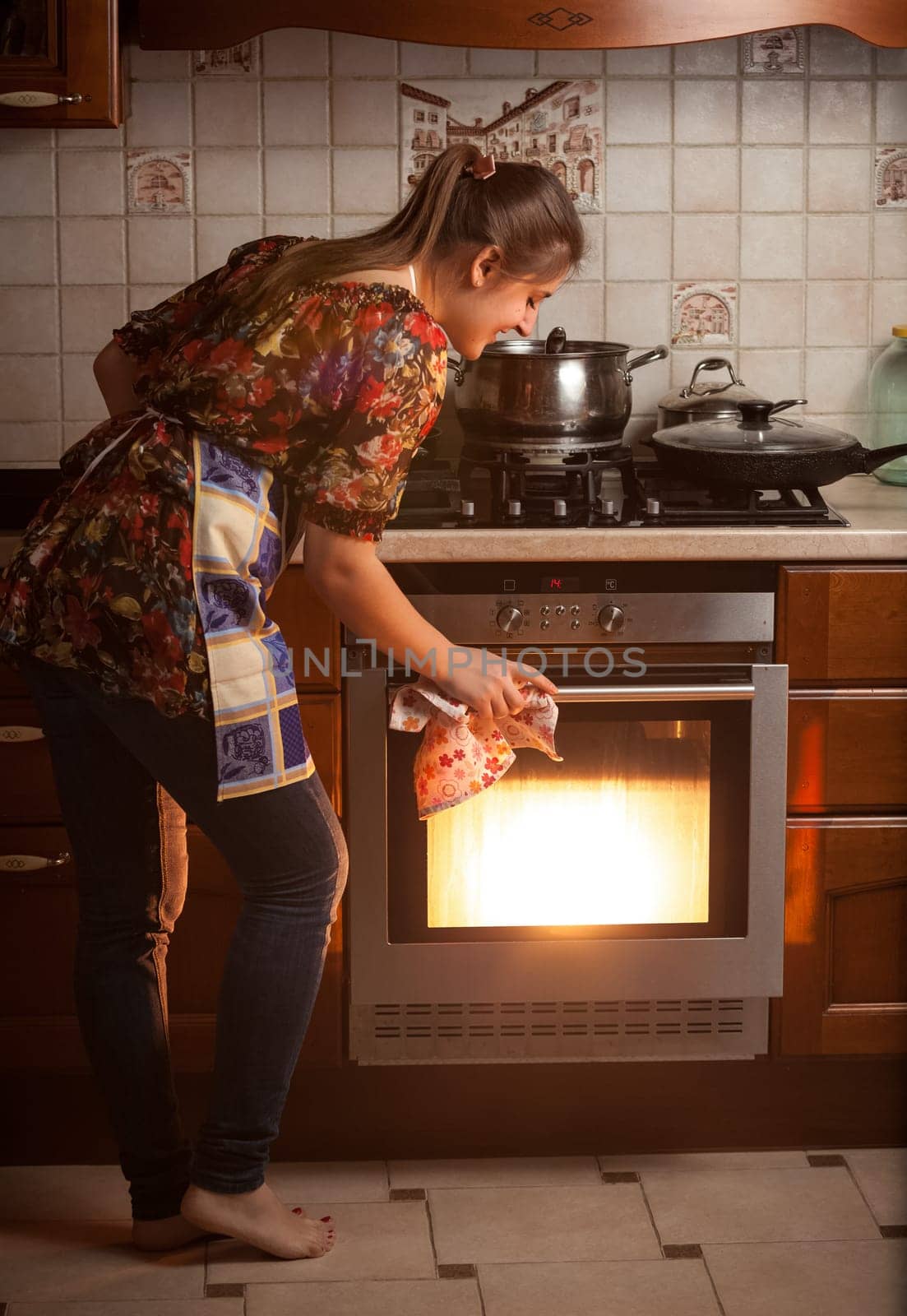 Young housewife checking dish cooking in oven