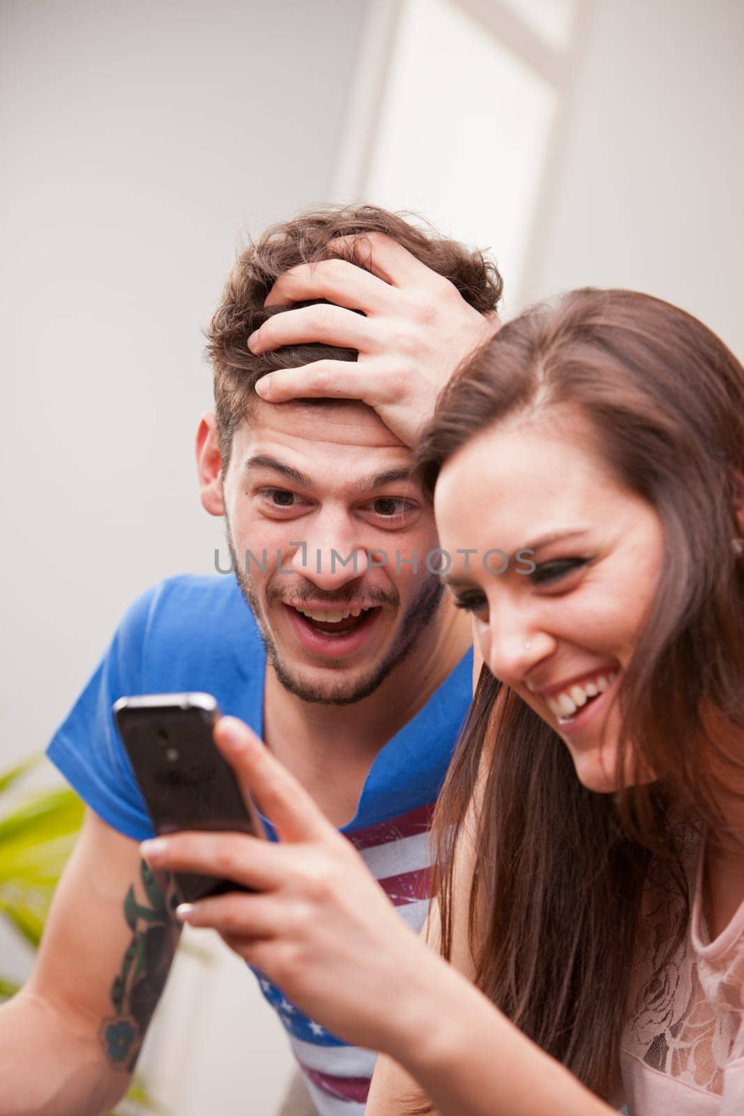 the girl is showing her phone to the boy and they are laughing because they're having fun and they are happy.