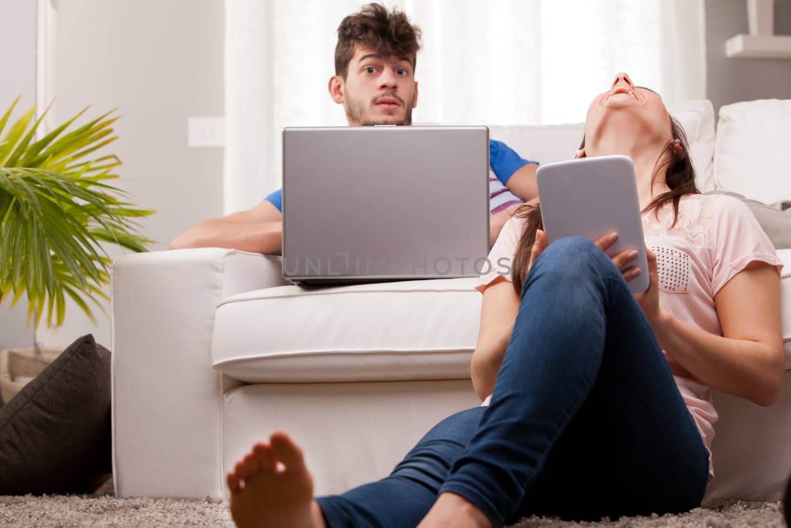 a man and a woman using a notebook and a tablet in their living room