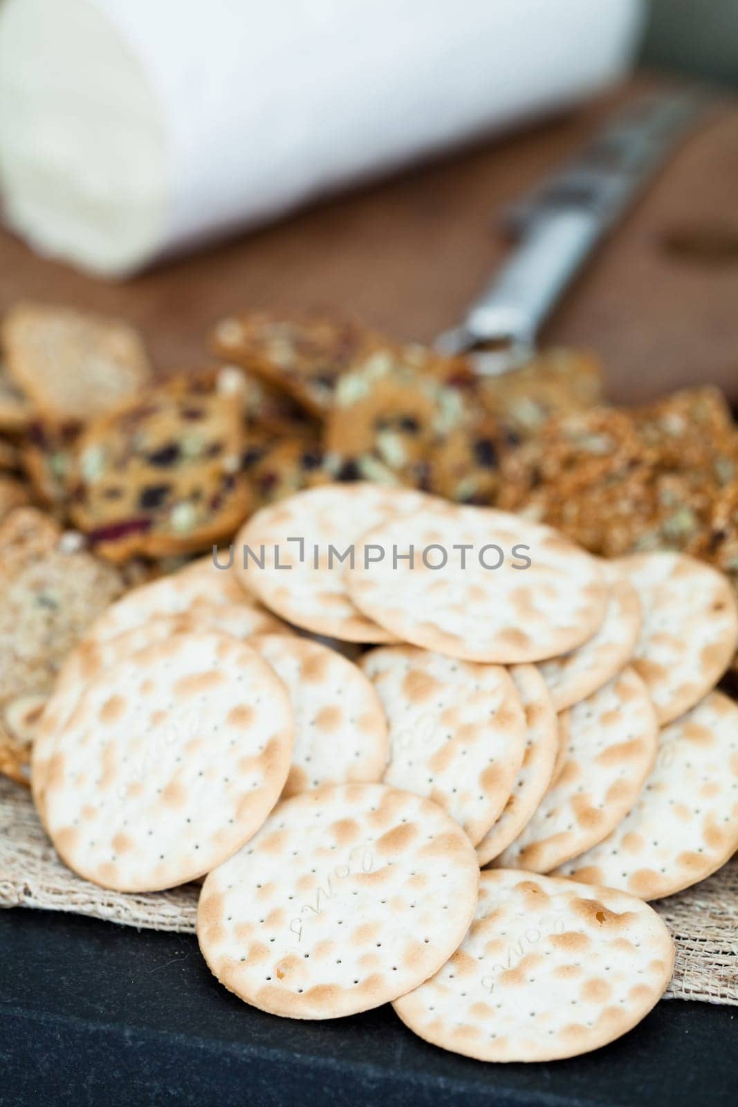 Closeup of dry wafer crackers with cheese on wooden cutting board in background