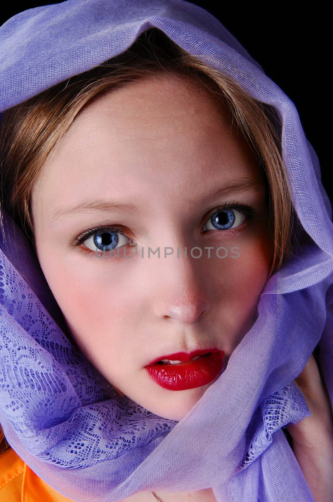 A beautiful young woman with blue eye's and a blue scarf around her.head, isolated for black background..