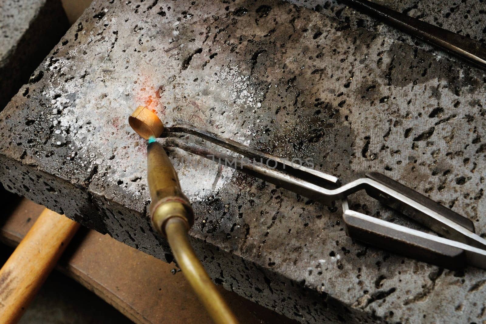 Skilled hands that create handmade jewelry with gold processing.