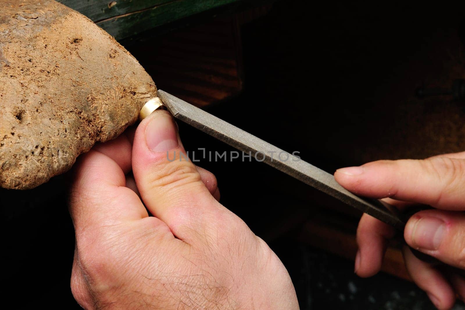 Skilled hands that create handmade jewelry with gold processing.