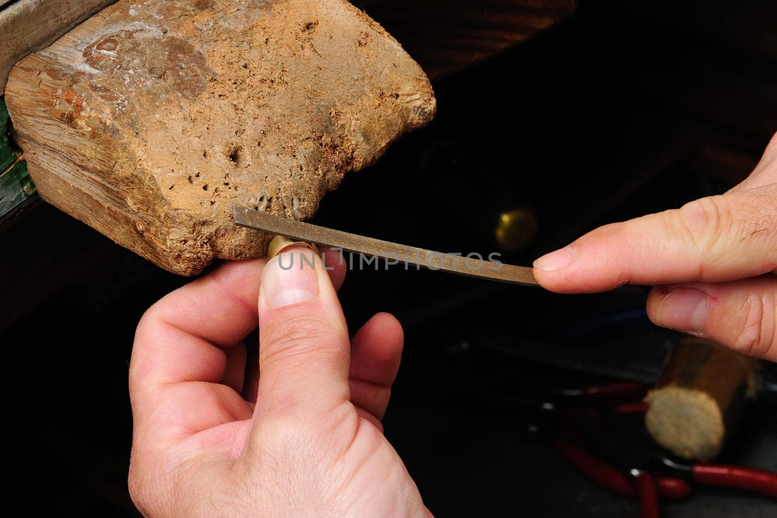 Skilled hands that create handmade jewelry with gold processing.