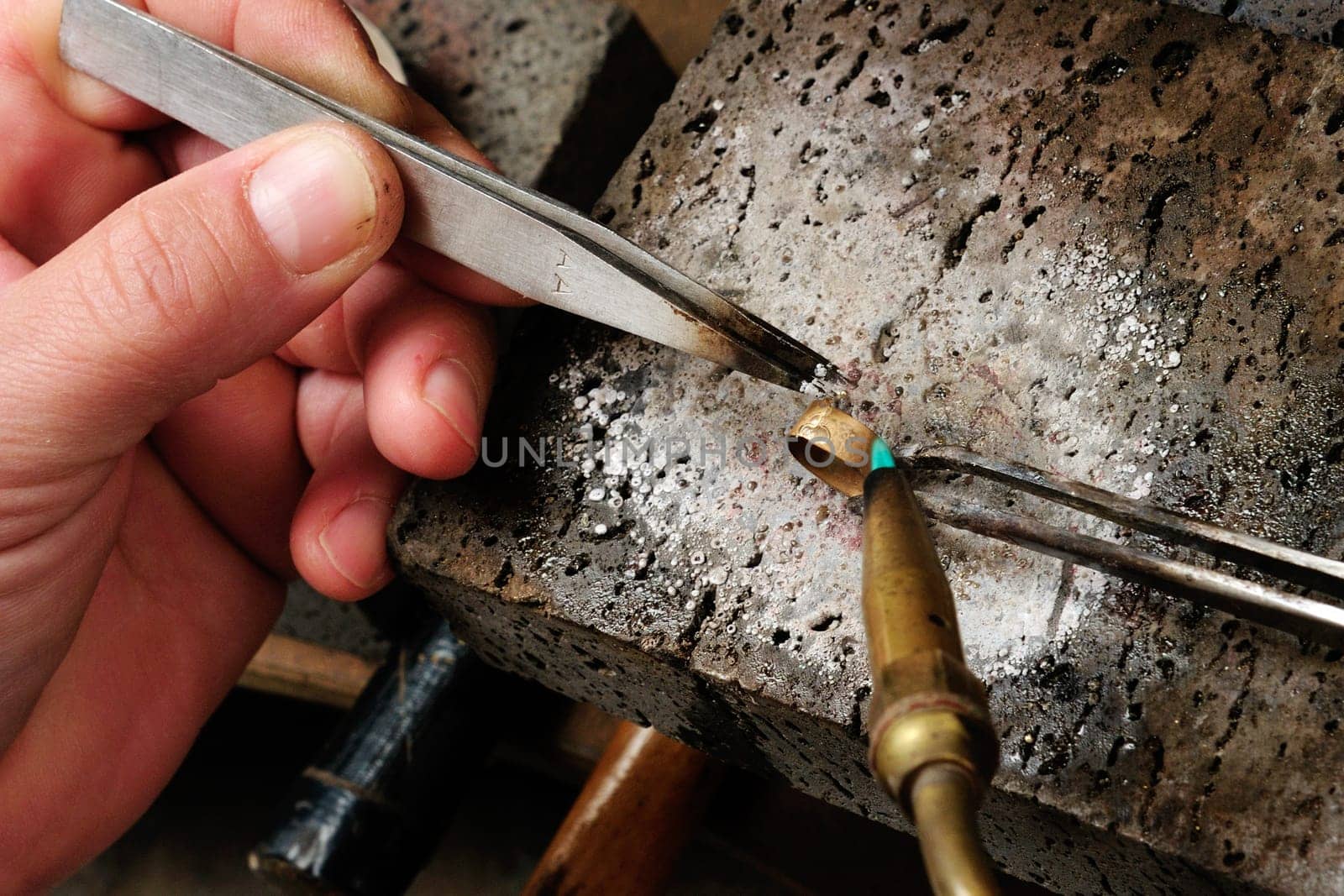 Skilled hands that create handmade jewelry with gold processing.