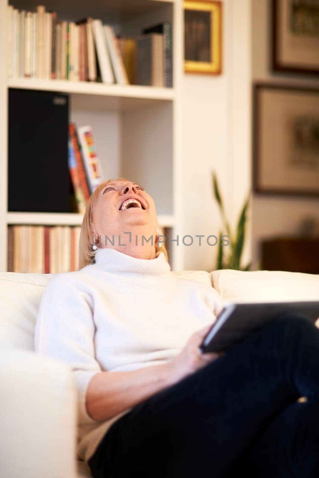 portrait of beautiful old woman using tablet pc and smiling, sitting on sofa at home