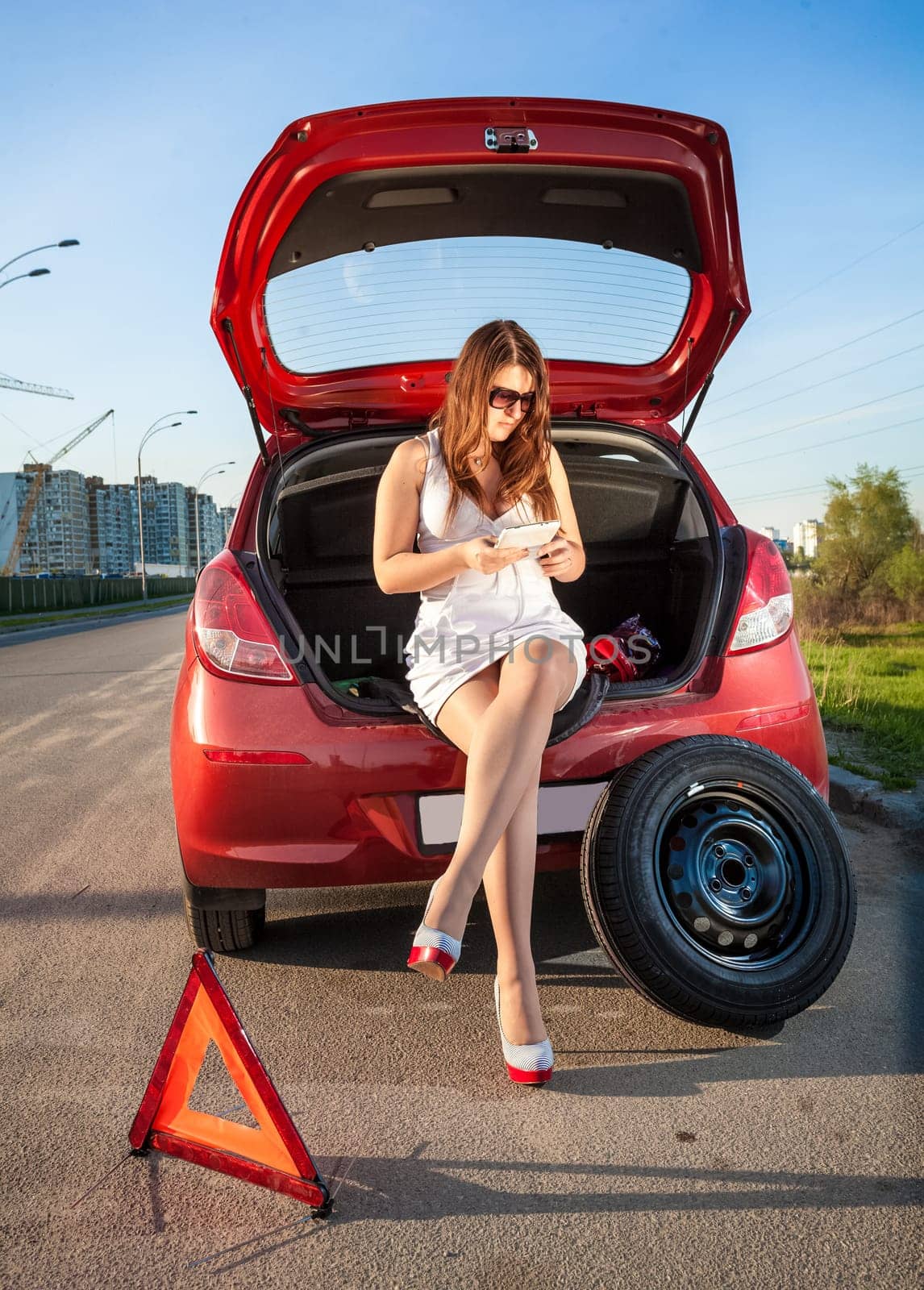Sexy woman in short dress browsing on tablet how to change wheel