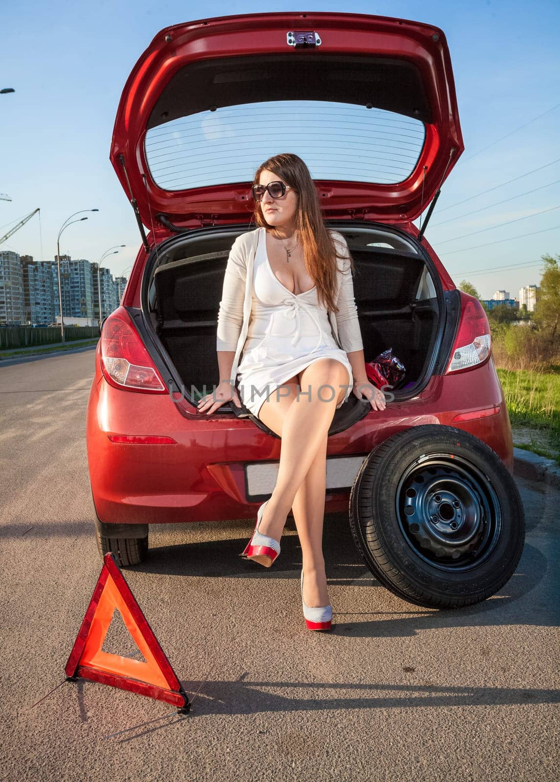 Sexy woman in short dress waiting for help near broken car