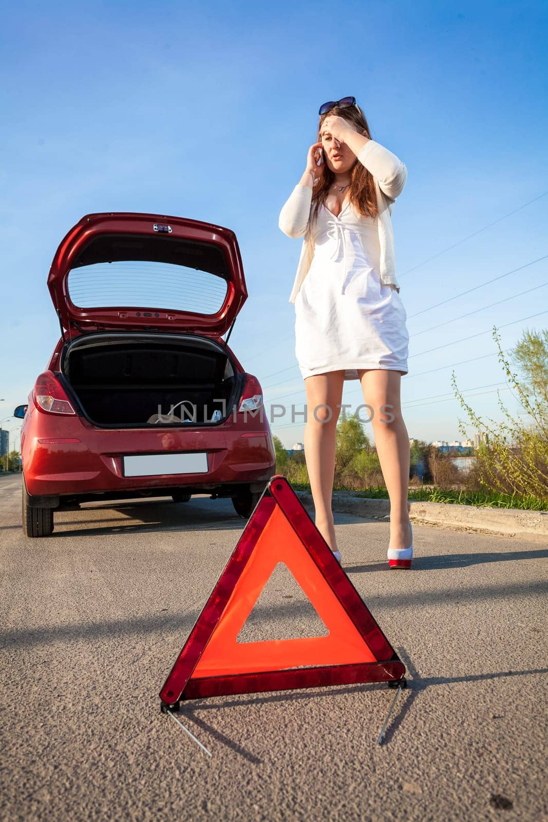 Depressed woman calling phone near crashed car