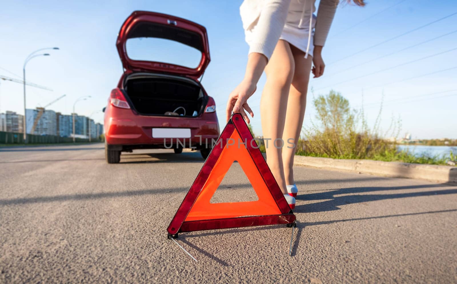 Closeup photo of woman putting warning sign after car crash