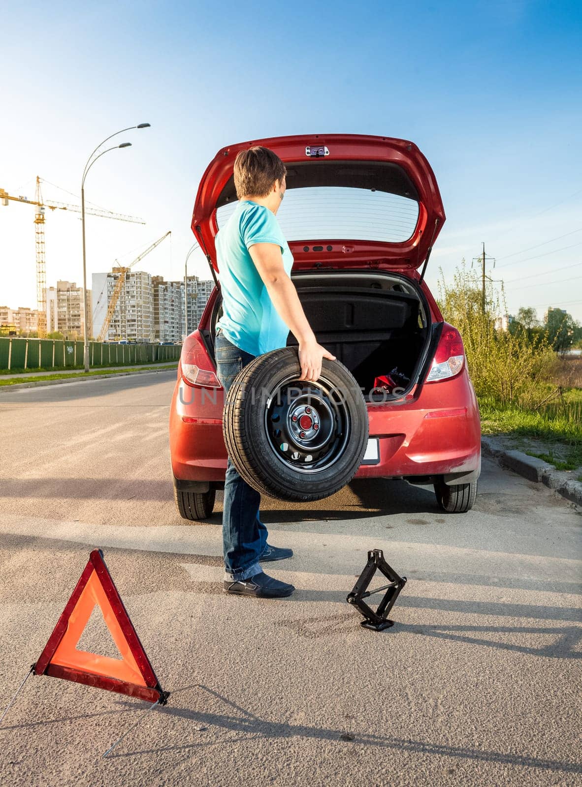 Photo of man taking spare wheel out of trunk