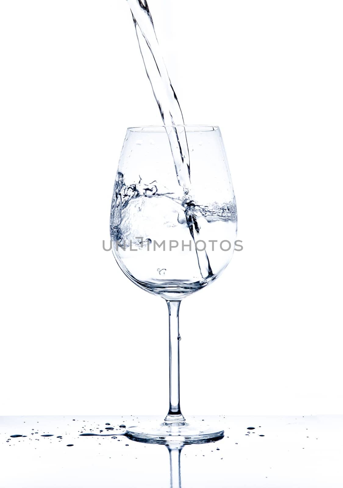 Glass with the stream of dinking water on white background