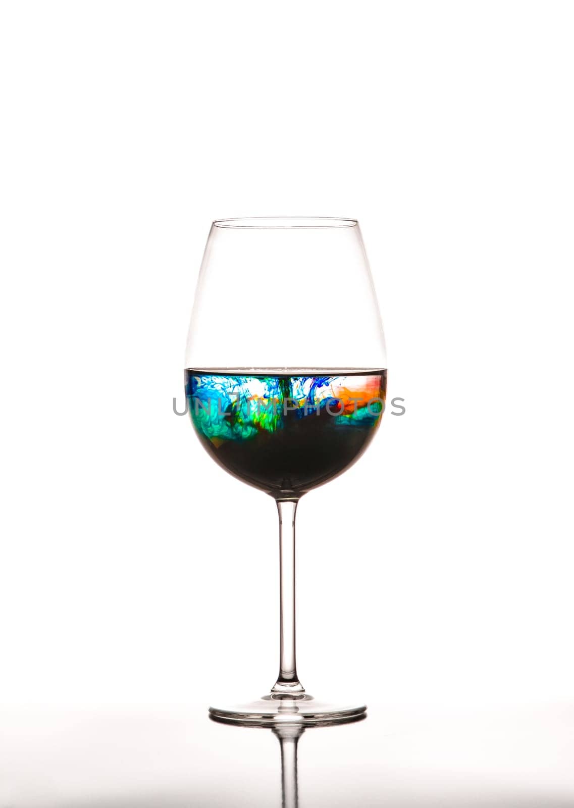 Glass with multicolored water on white background, concept of polution