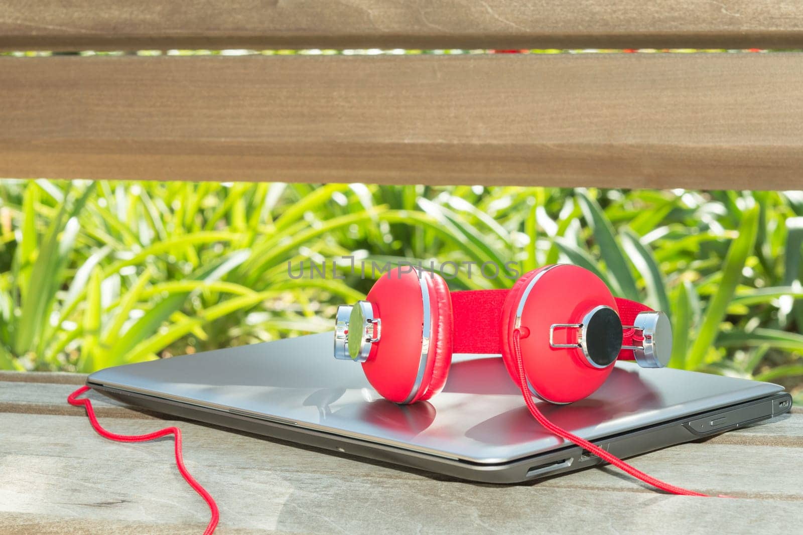 Colorful red headphones and notebook on the wood bench in yard