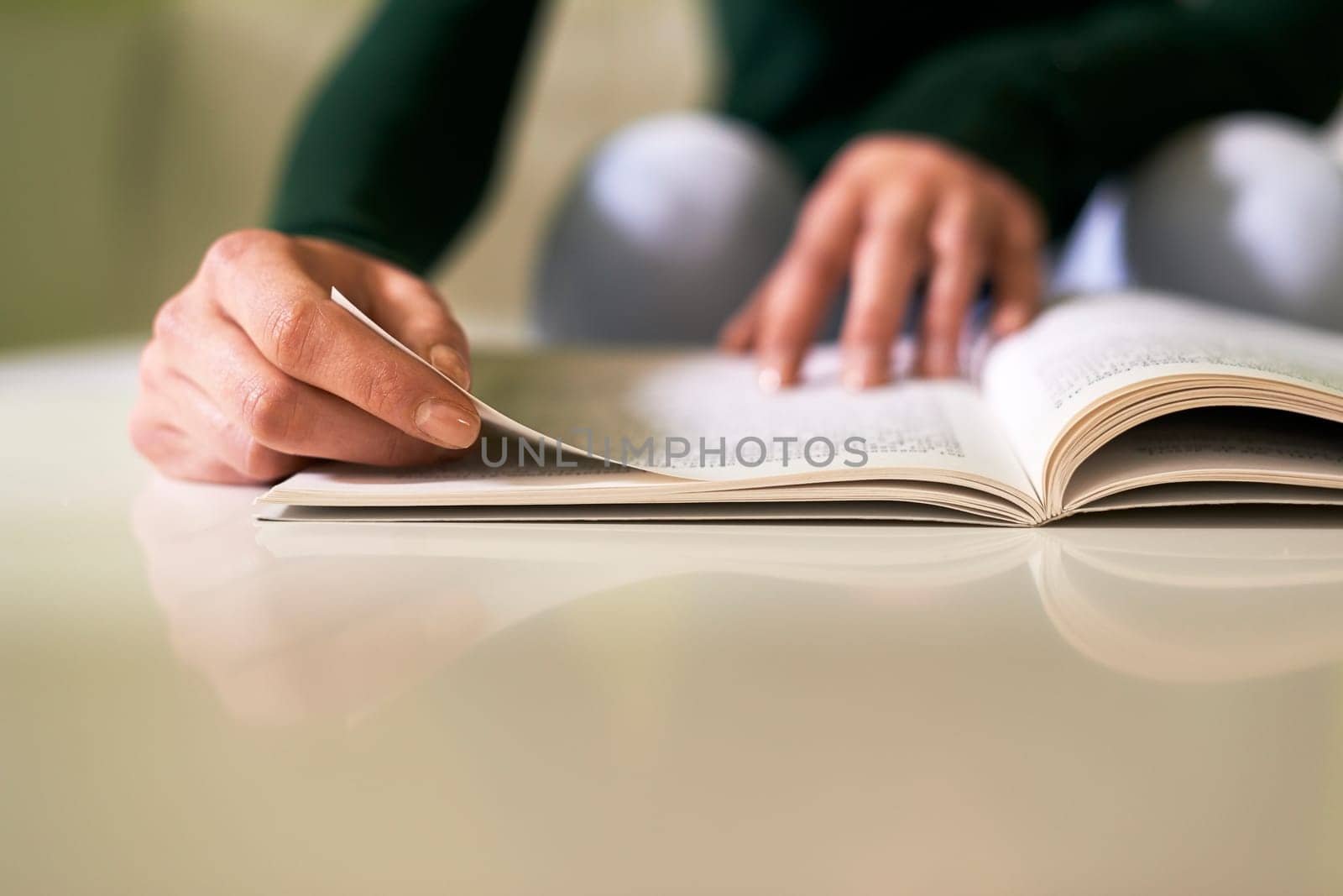 young caucasian woman reading book at home, sitting on sofa. Copy space on table