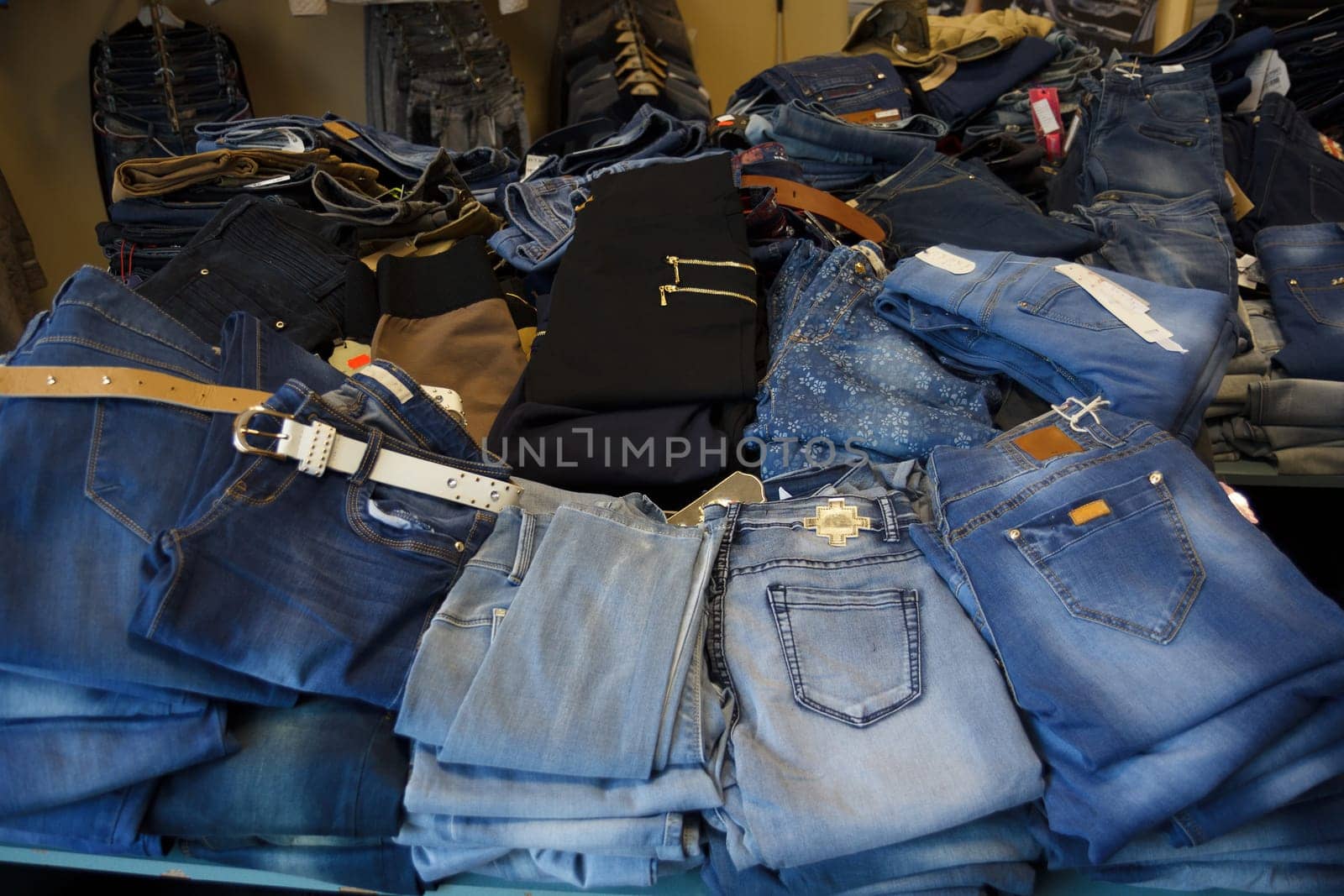 heap of jeans in small jeans store