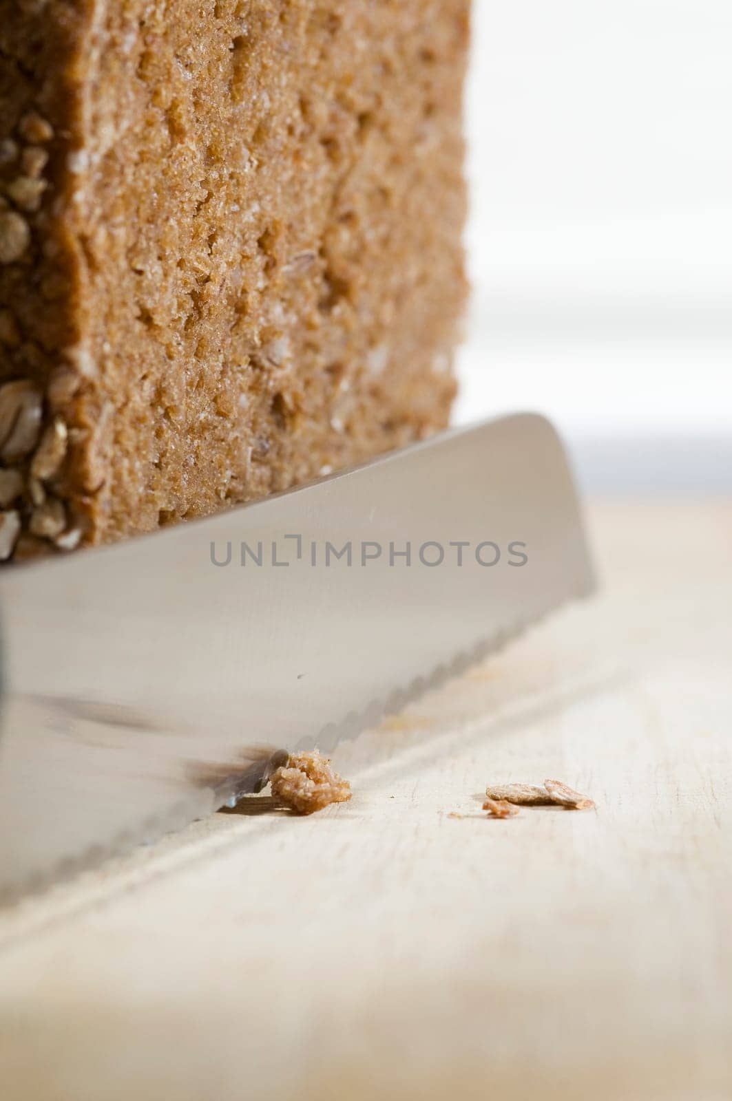 Still life with wholemeal bread and bread knife on cutting board against a bright background