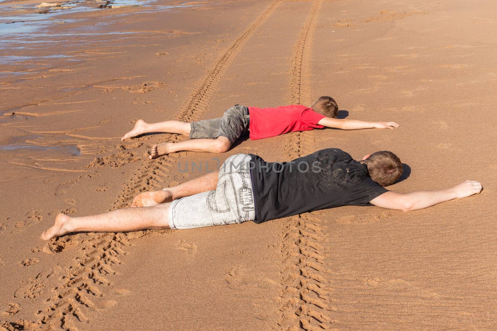 Teen boys family hangout playtime at the  beach ocean on clear blue day