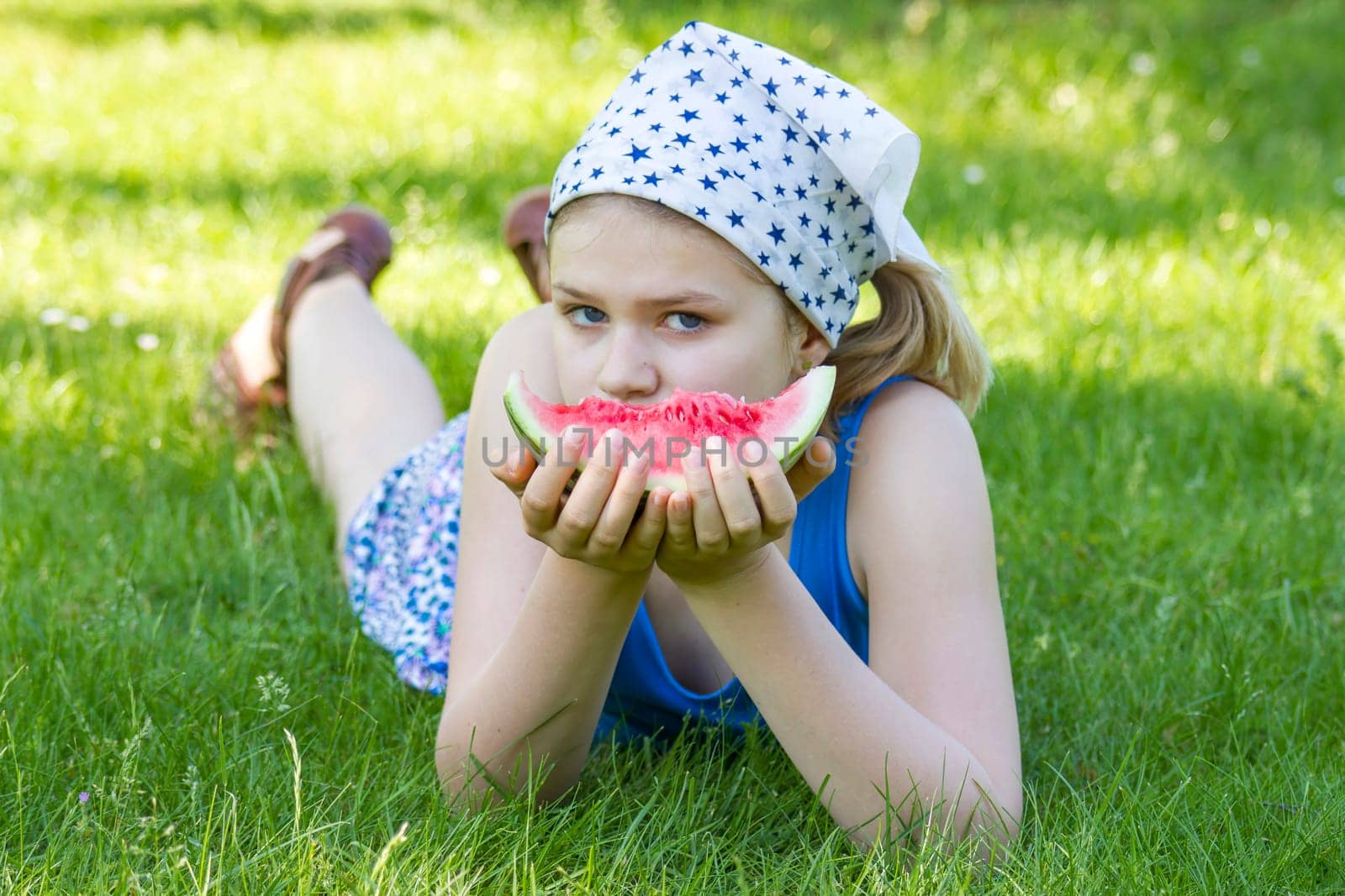 cute little girl eating watermelon on the grass