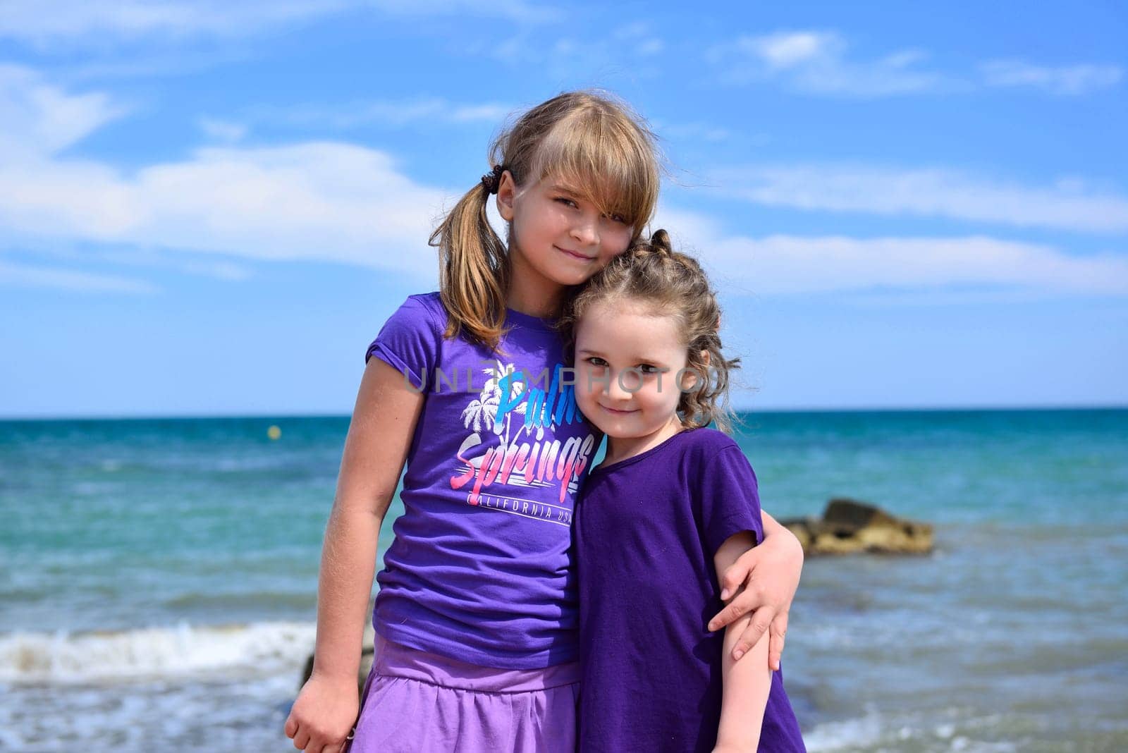 Two little sisters posing on the beach on a nice summer day, Costa Blanca, Spain