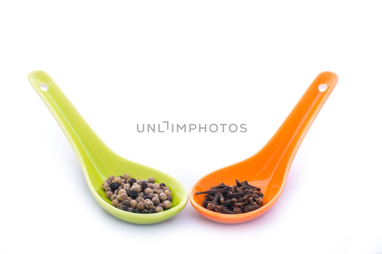 Pepper grains and cloves in two ceramic spoons