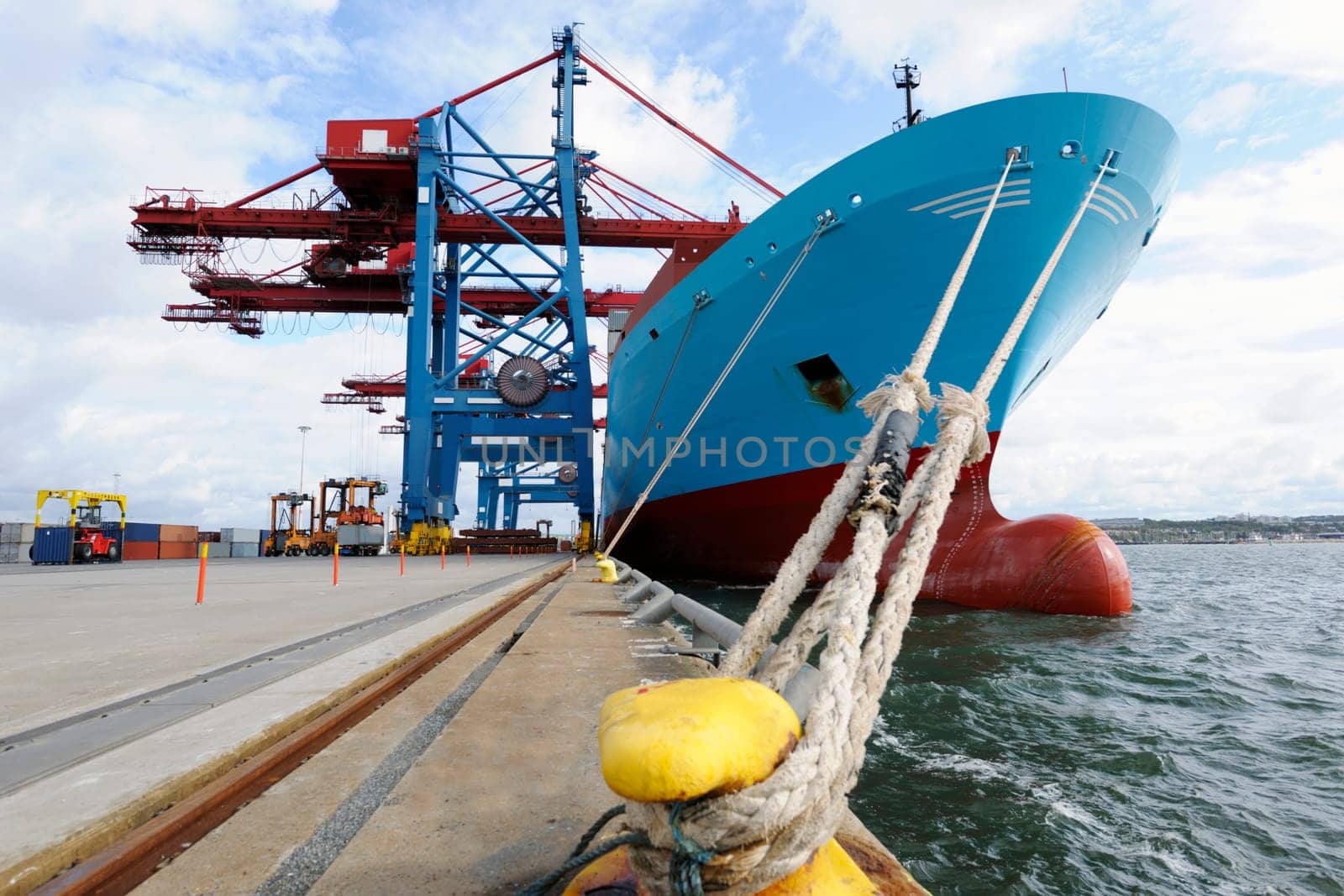 large container-ship mored at quay-side, container-cranes and general port activities.