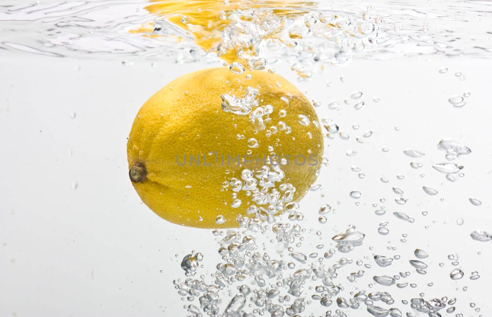 Bubbles forming in blue water after lemon is dropped into it