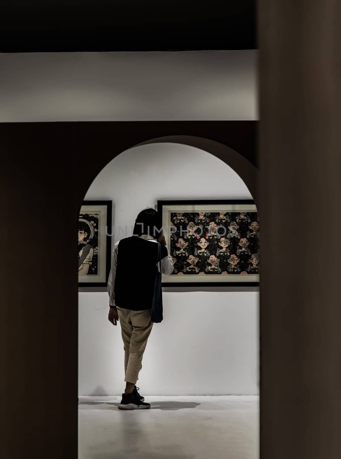 Bangkok, Thailand. Feb - 06, 2022 : Back view of young asian man standing interested in photograph displayed on white wall at art gallery exhibition hall. Concept of fine art in photographic. No focus, specifically.