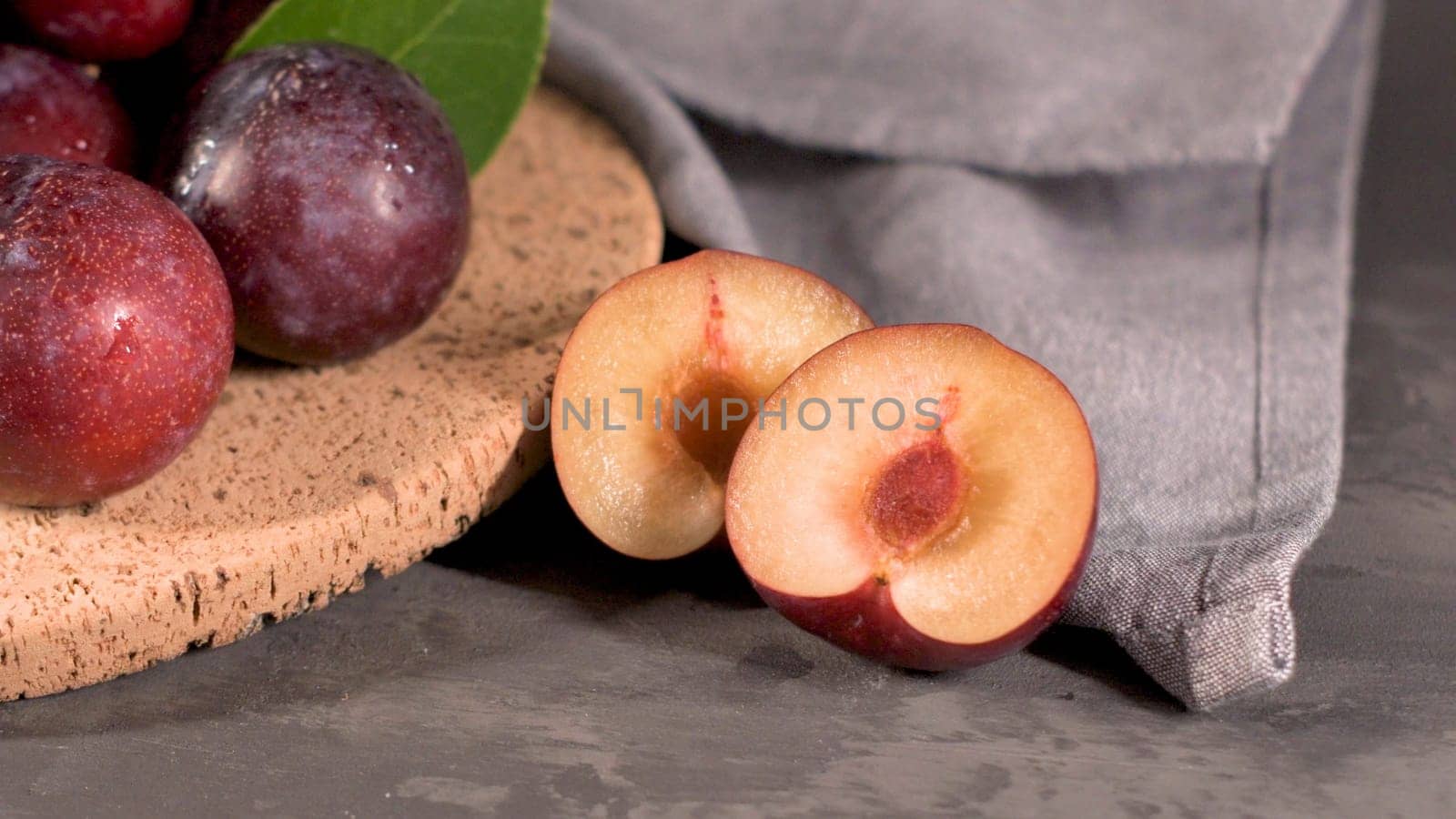 Delicious red plums in a cork plate on kitchen countertop.