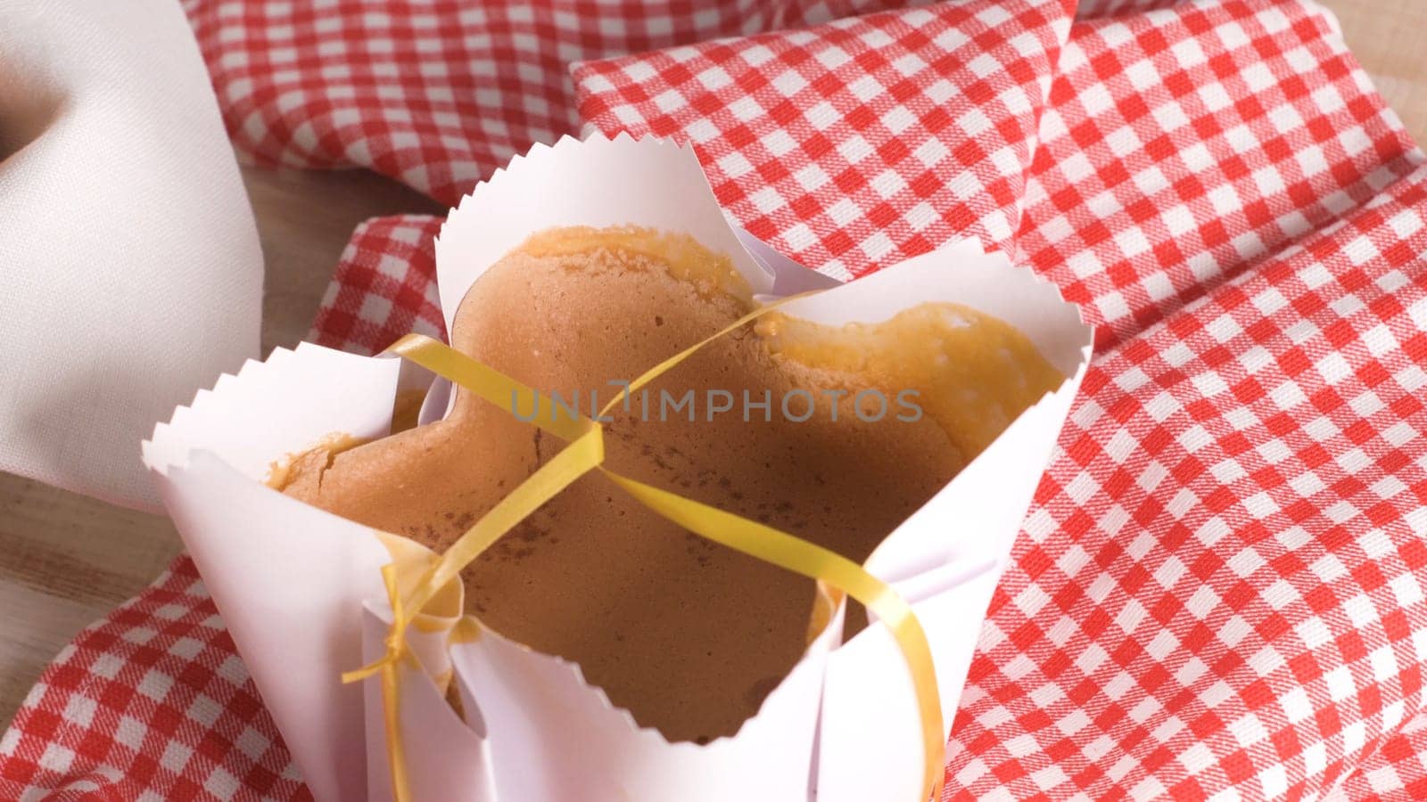 Portuguese sponge cake wrapped in the typical paper used on the baking, on wooden background.