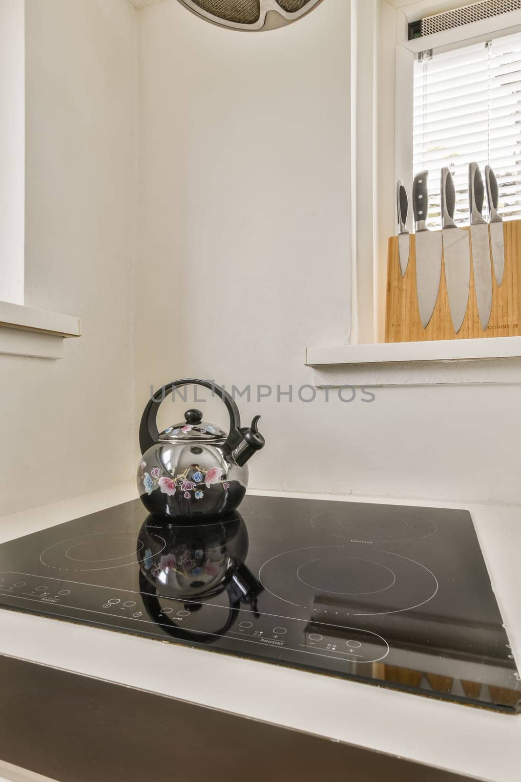 a tea kettle sitting on top of a stove in a kitchen with white walls and wood trim around the edges