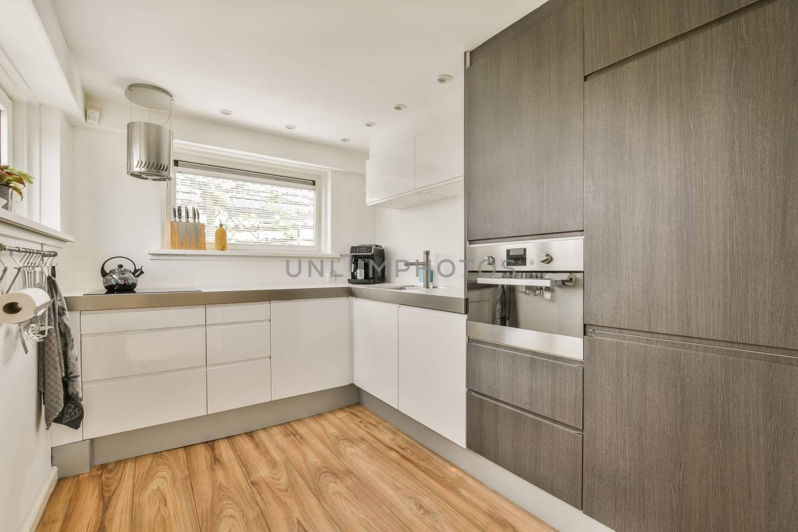 a kitchen with white cabinets and wood floors by casamedia