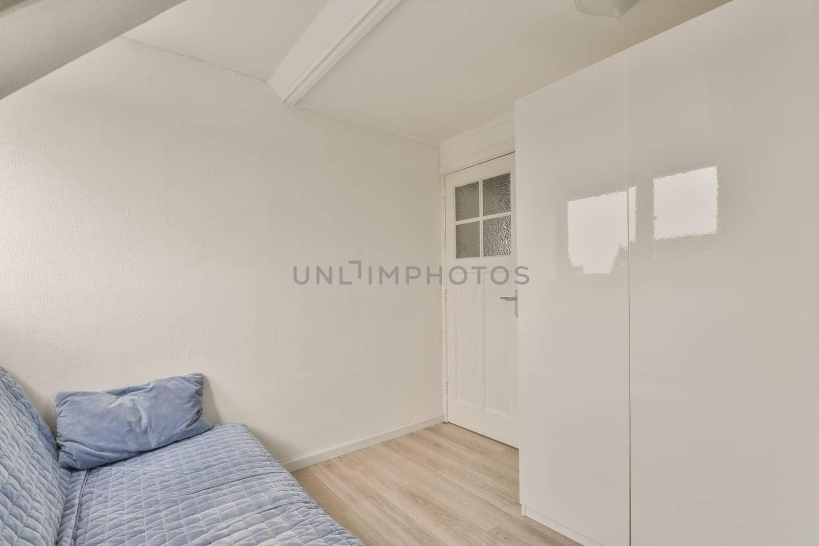 a bedroom with white walls and light wood flooring in the middle of the room, there is a bed on the right side