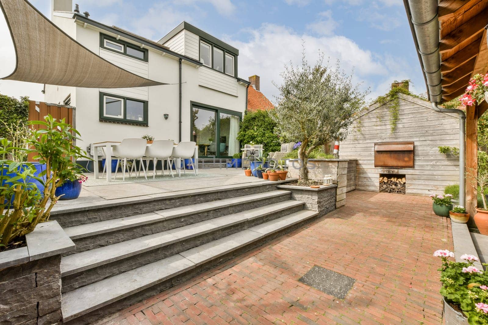 an outside area with some plants and flowers on the steps in front of a house that has been painted white