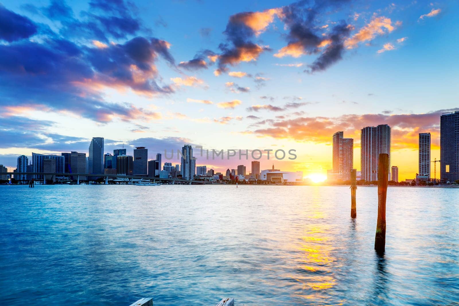 Miami city skyline panorama at dusk with urban skyscrapers over sea with reflection