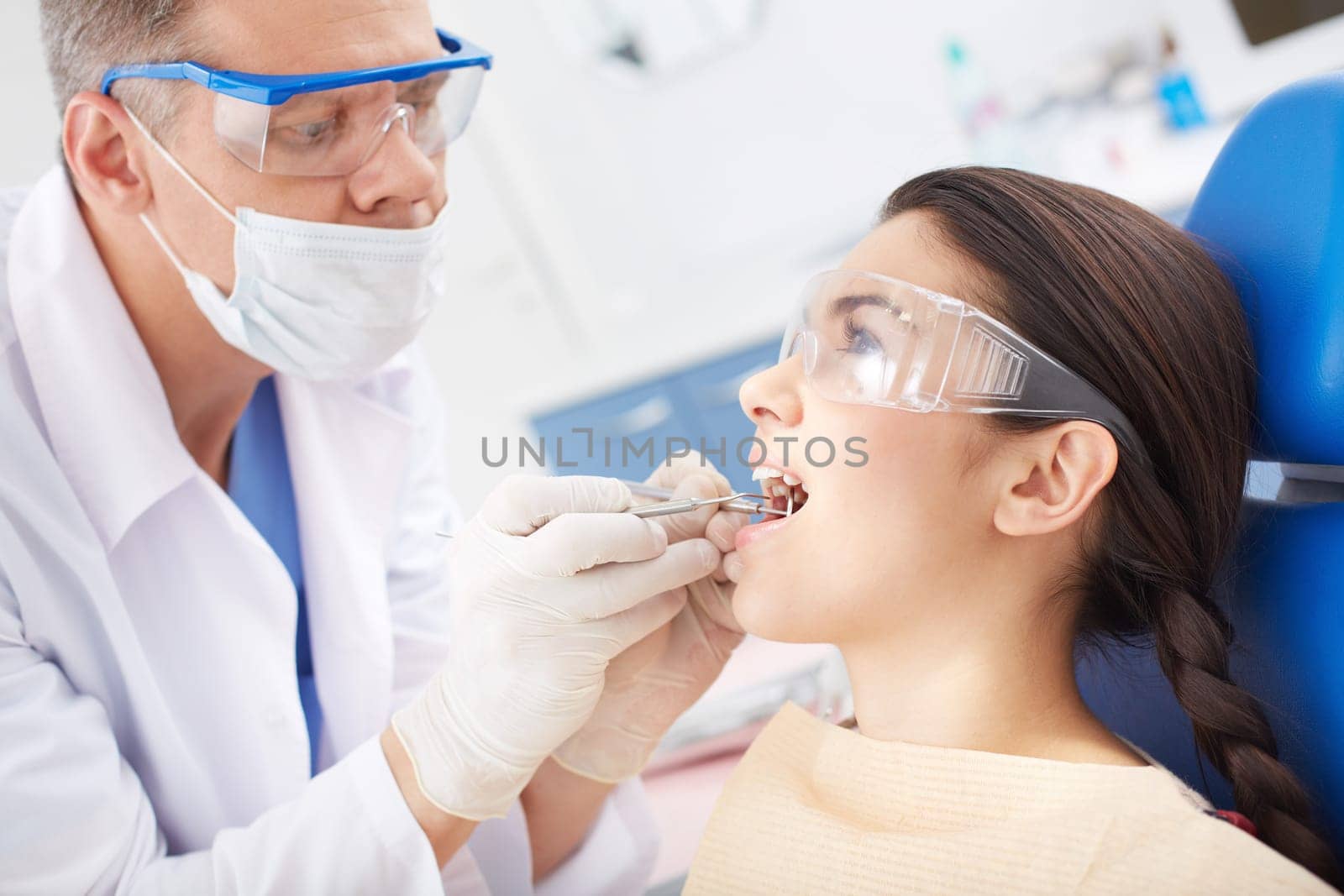 Young girl with open mouth during oral checkup at the dentist’s
