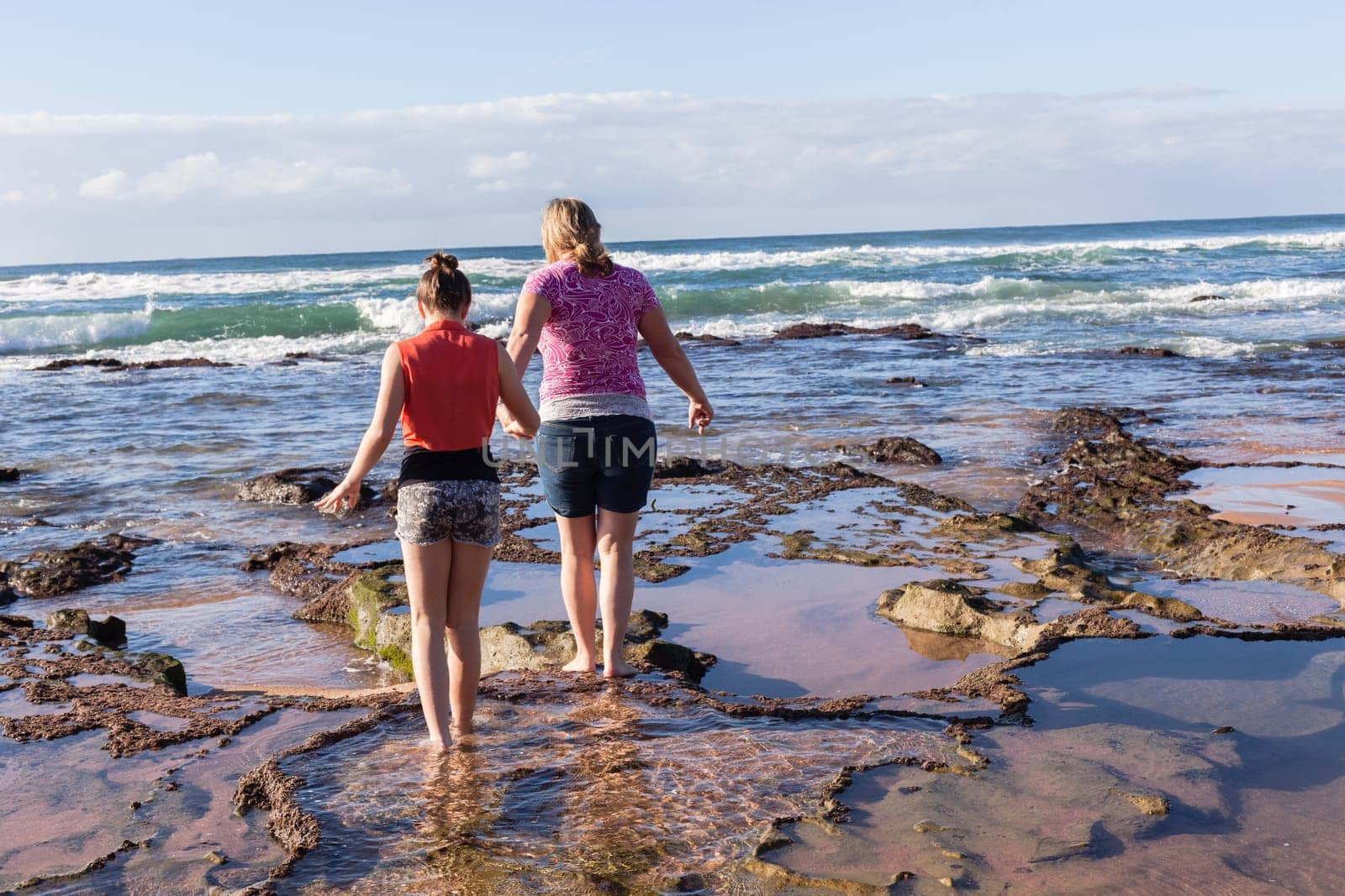 Girls mother daughter together exploring ocean beach rock reefs pools at low tide