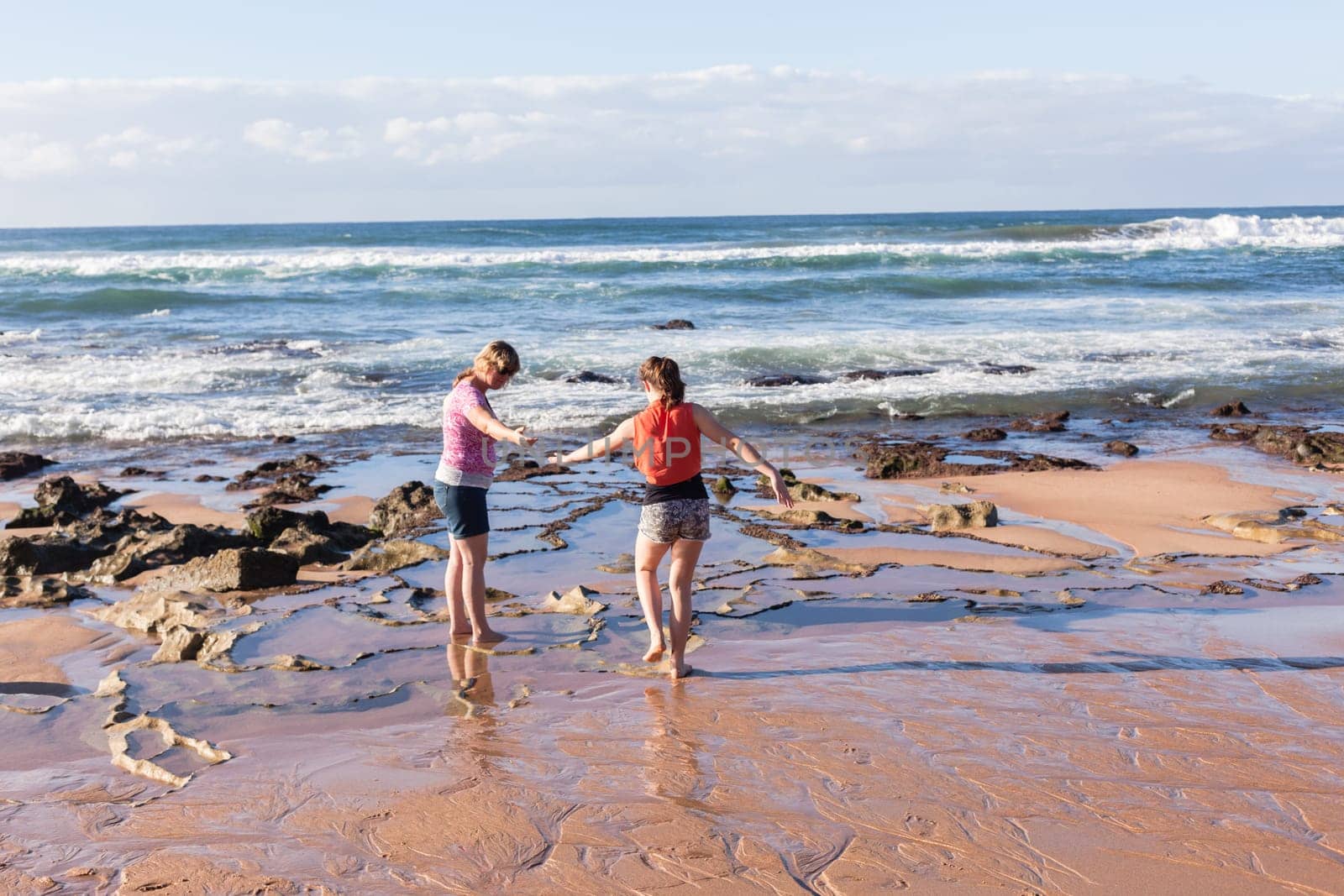 Girls mother daughter together exploring ocean beach rock reefs pools at low tide