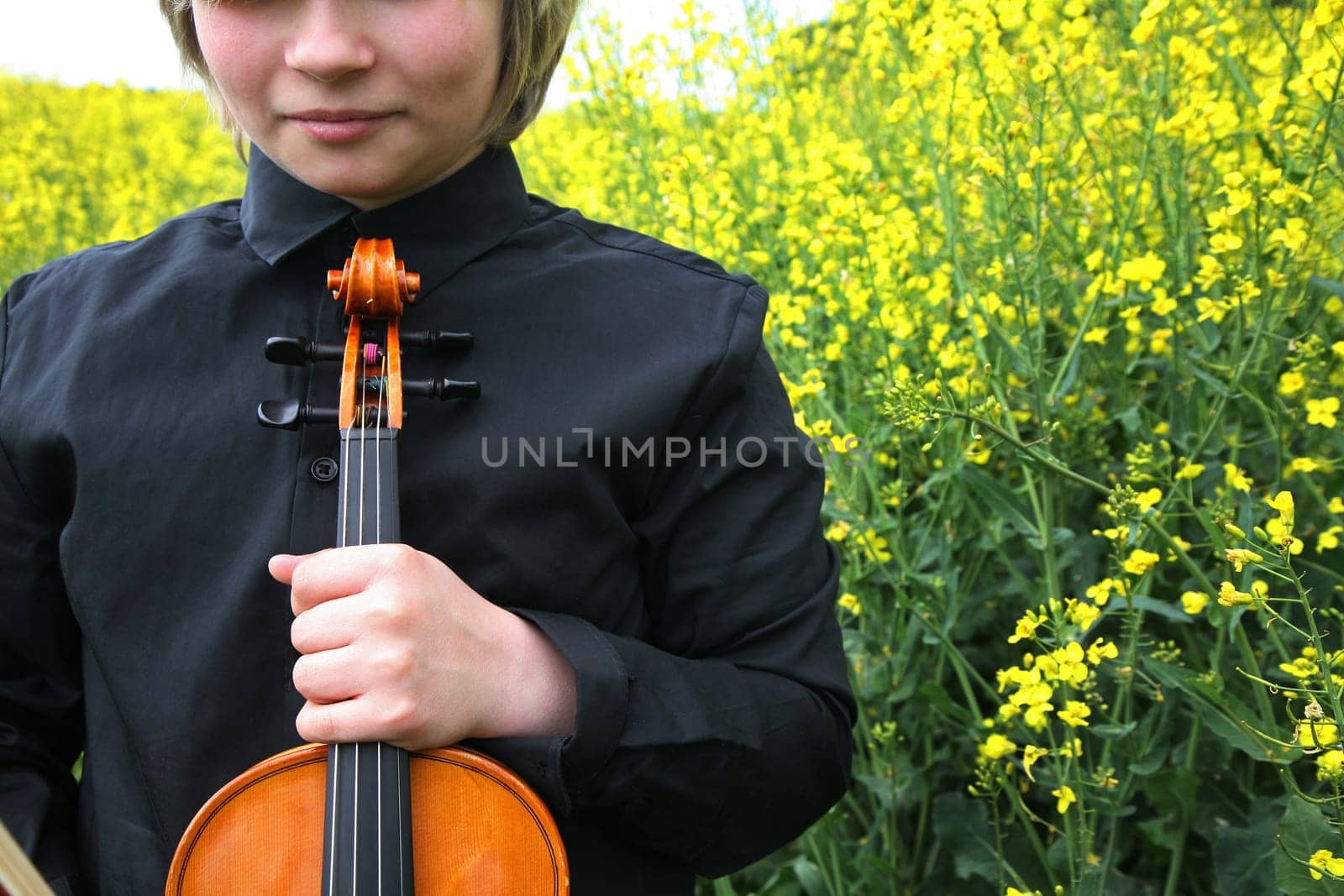 Young man with violin in the rapefield