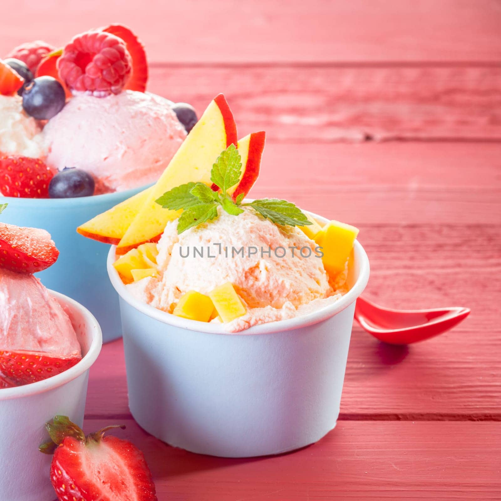 Individual servings of cool refreshing ice-cream topped with fresh tropical fruit including apple, strawberries, blueberries and raspberries, square format with copyspace