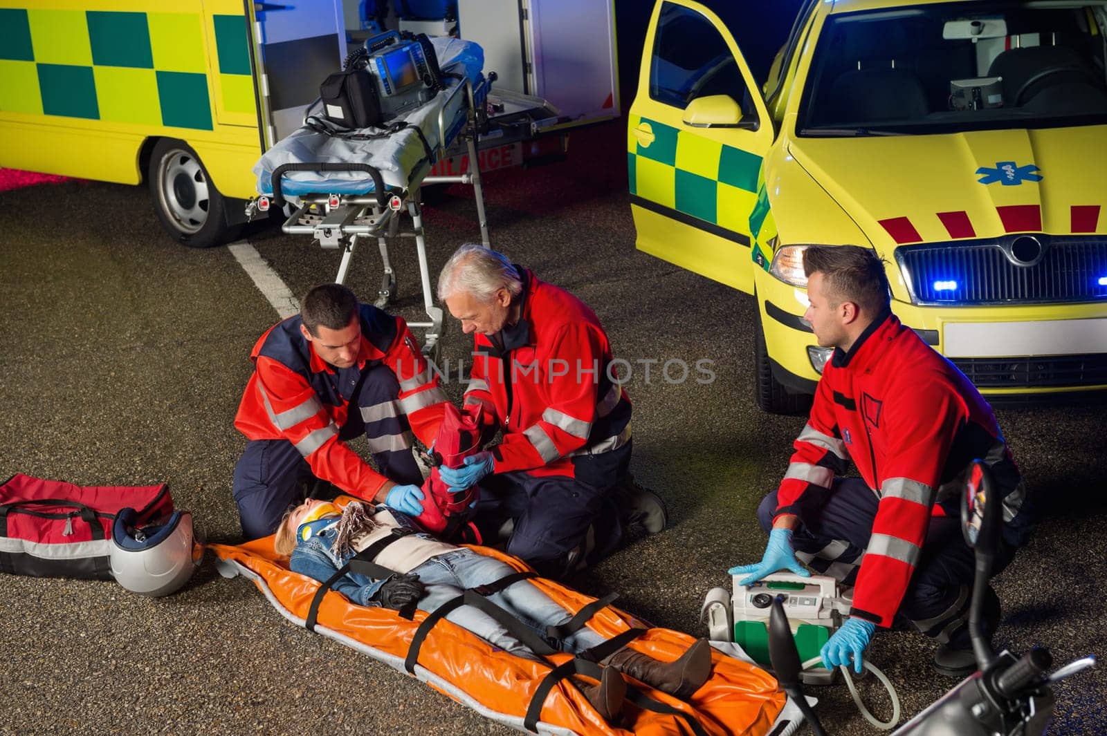 Paramedics helping injured woman motorbike driver on stretcher at night