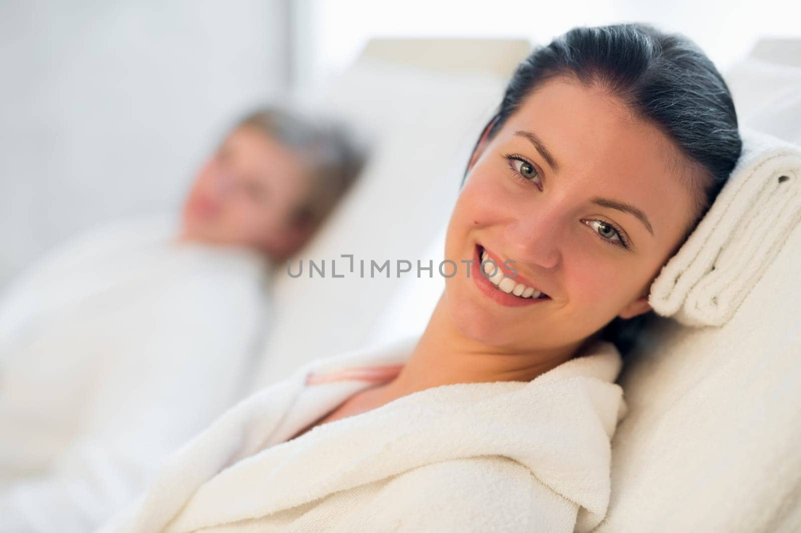 Smiling woman resting at beauty spa room friend in background