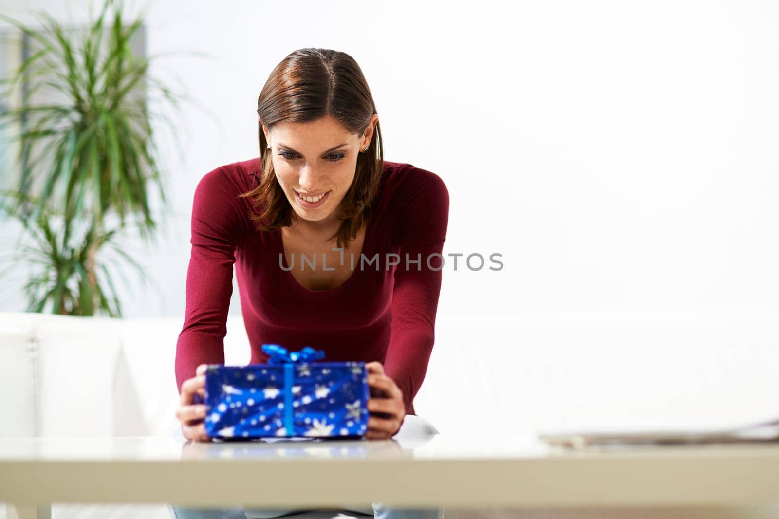 caucasian young woman getting present and smiling, sitting on sofa at home