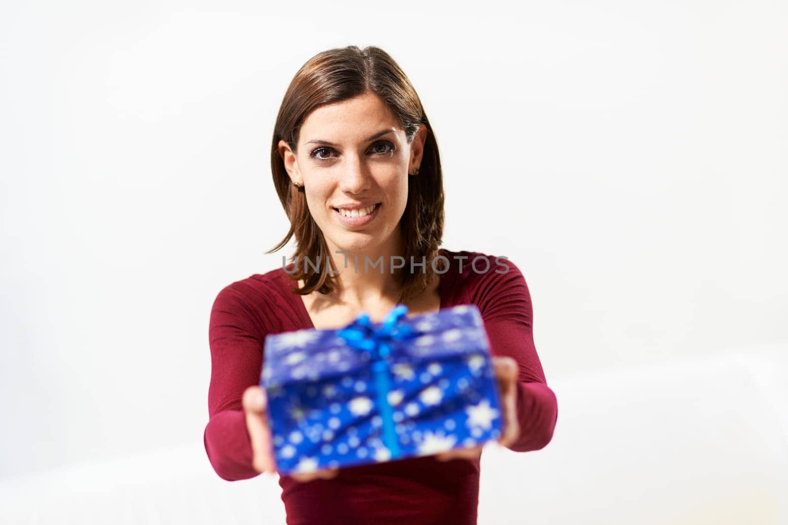 caucasian young woman showing present to the camera and smiling on white background