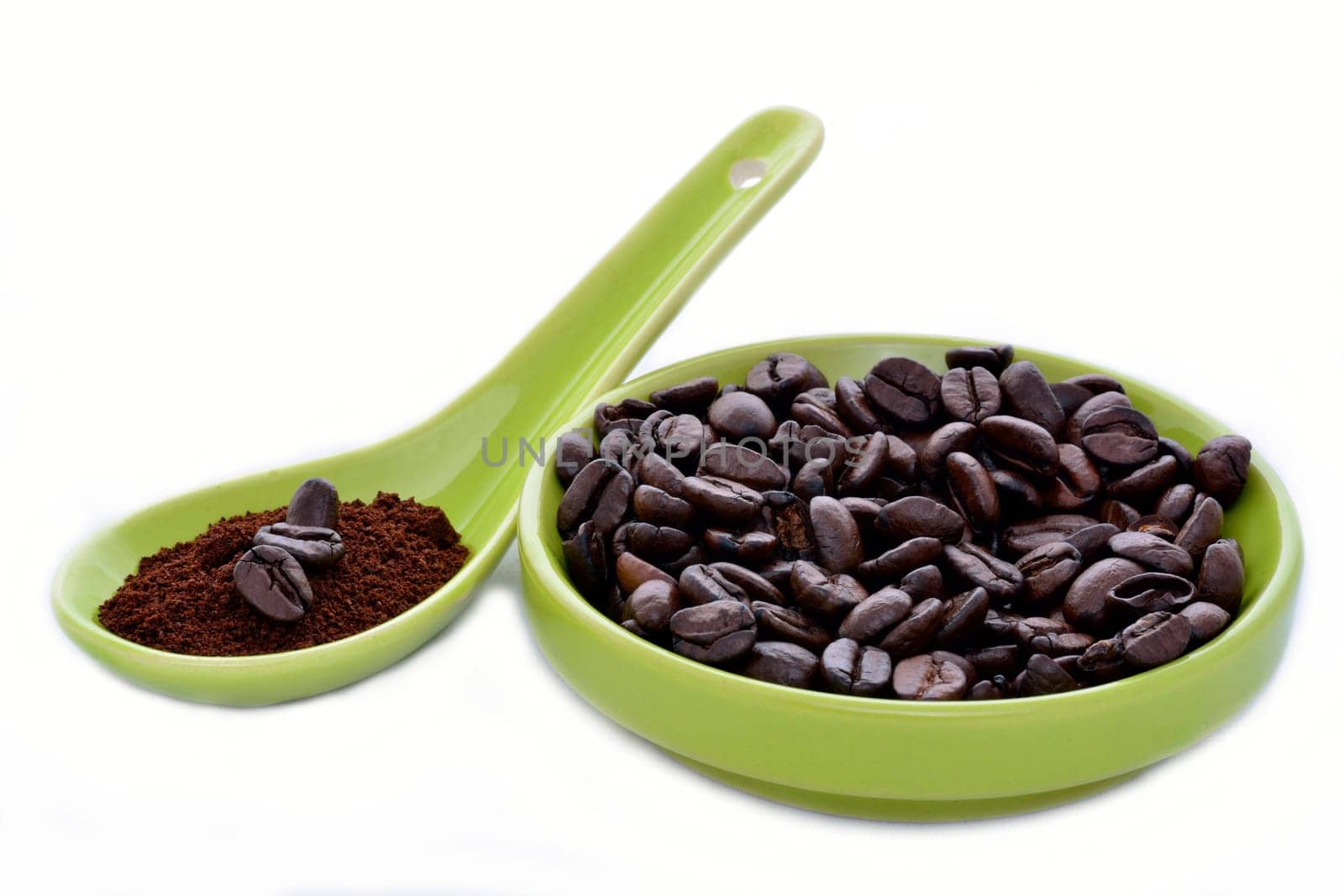 A green ceramic spoon and saucer with coffe beans on a white backgroun