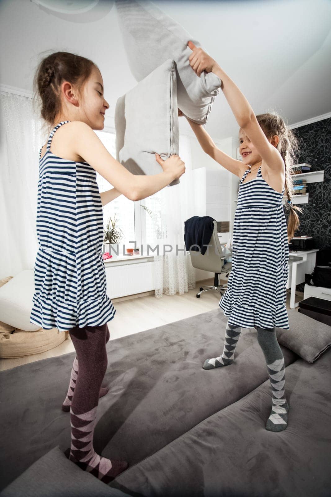 Photo of children having fight with pillows on bed