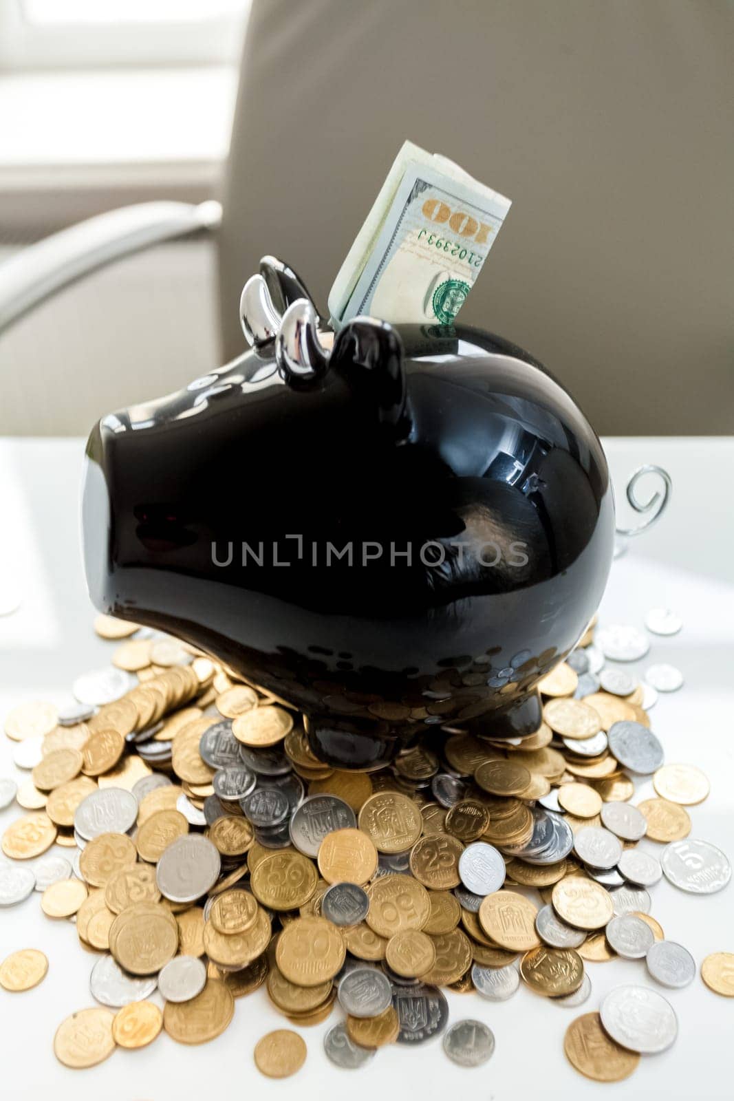 Closeup photo of piggy bank on pile of money with dollars in slot