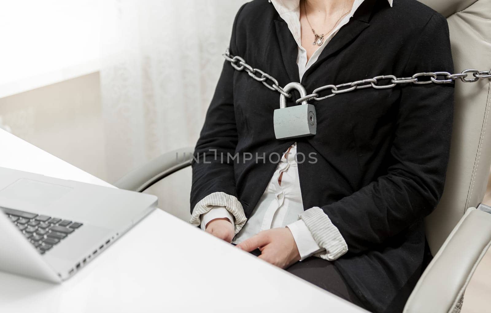 Closeup photo of businesswoman tied to chair by metal chain